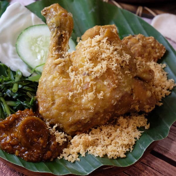 Our ayam penyet with crispy kremes, sambal and fresh vegetables on a banana leaf